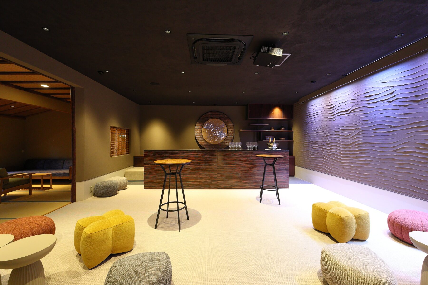 縁和の室内全景。カウンターの奥に円窓「澪」、右手に波打つ左官壁「水明かり」、ゆったりとしたスツールが置かれている